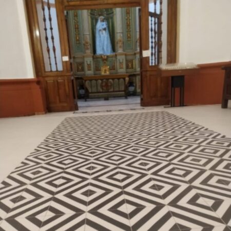 Detalle del suelo hidráulico geométrico en blanco y negro instalado por Adrihosan en el interior de una iglesia.