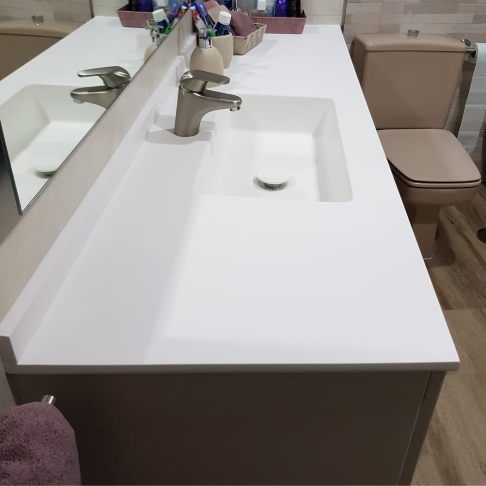 Encimera de baño blanca con lavabo integrado en superficie sólida, diseño moderno y sin juntas.