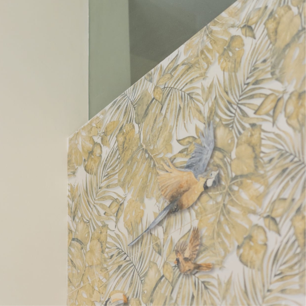 Primer plano de papel pintado tropical con hojas verdes y loros en tonos cálidos.