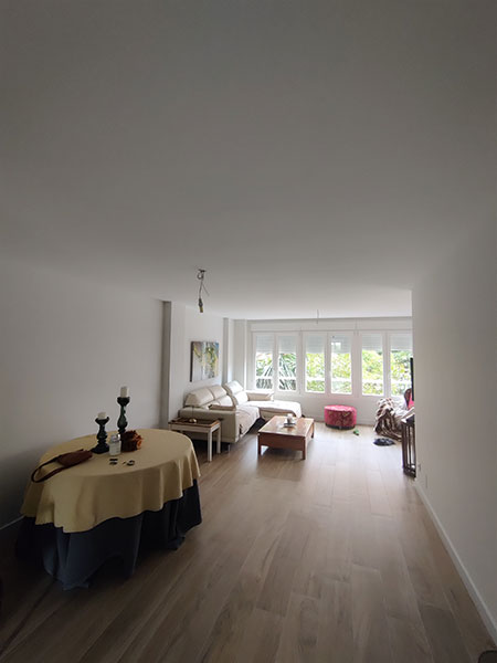 Reforma con esencia natural y armonía contemporánea 6 Salón reformado con suelo porcelánico efecto madera, ventanales blancos y decoración minimalista en Alicante