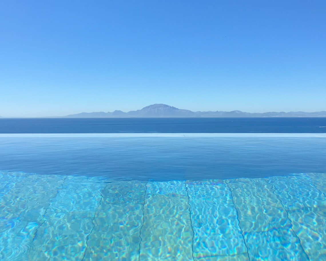 Piscina infinita revestida con azulejos Adrihosan, agua cristalina y vistas al mar Mediterráneo con la costa africana al fondo