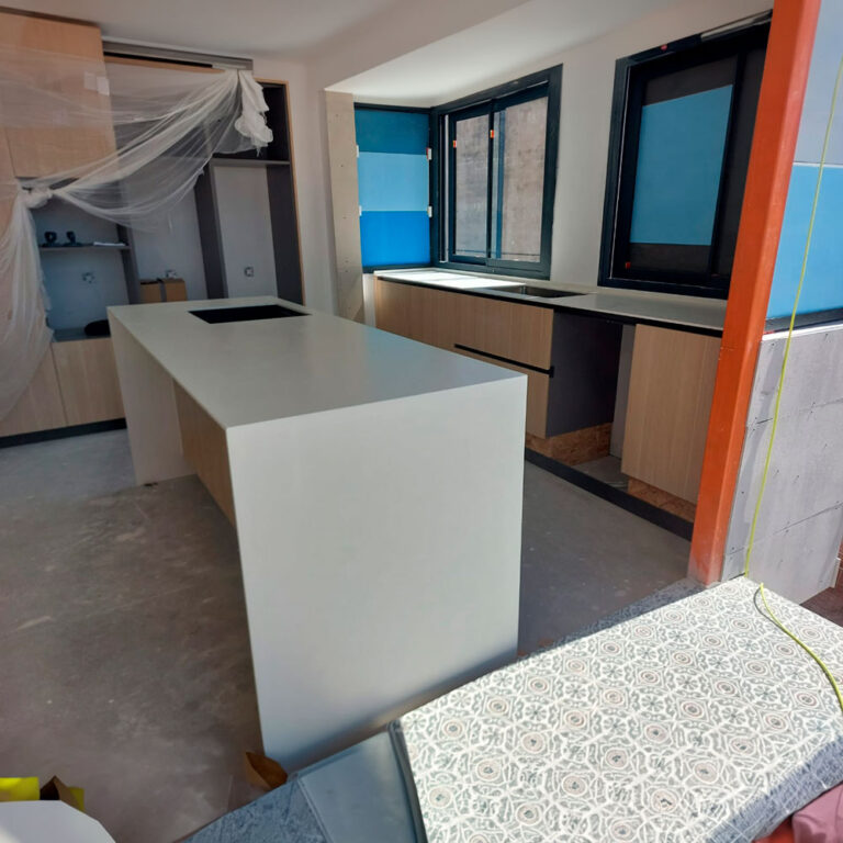 Cocina abierta en proceso de instalación con isla blanca y muebles en madera clara