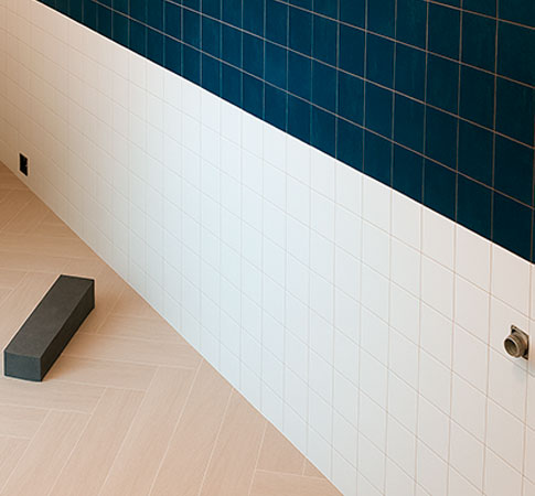 Azulejo precorte blanco liso instalado en pared durante obra de cocina con combinación en azul