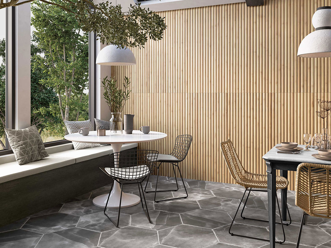 Comedor moderno con pared revestida de azulejo porcelánico efecto bambú y suelo hexagonal de mármol oscuro junto a un gran ventanal.