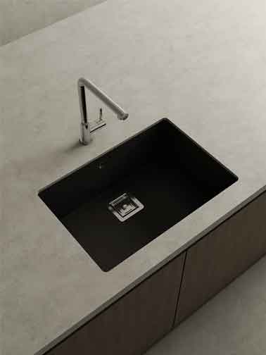 Fregadero negro integrado en encimera clara con grifo cromado de diseño moderno