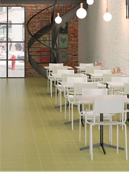 Pavimento Porcelánico 15x15 Rainbow en Tono Pistacho (0,5 m2/cj) 2 Suelo de baldosas verdes en cafetería de estilo industrial con sillas blancas y pared de ladrillo