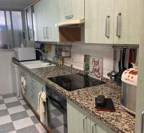 Imagen del antes de una reforma de cocina, con encimera de granito marrón y muebles verdes claros antes de instalar la encimera de cocina Concerto