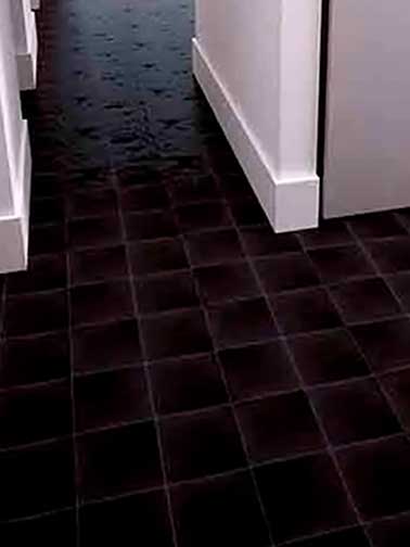 Suelo de baldosas cuadradas negras en un pasillo con paredes blancas.