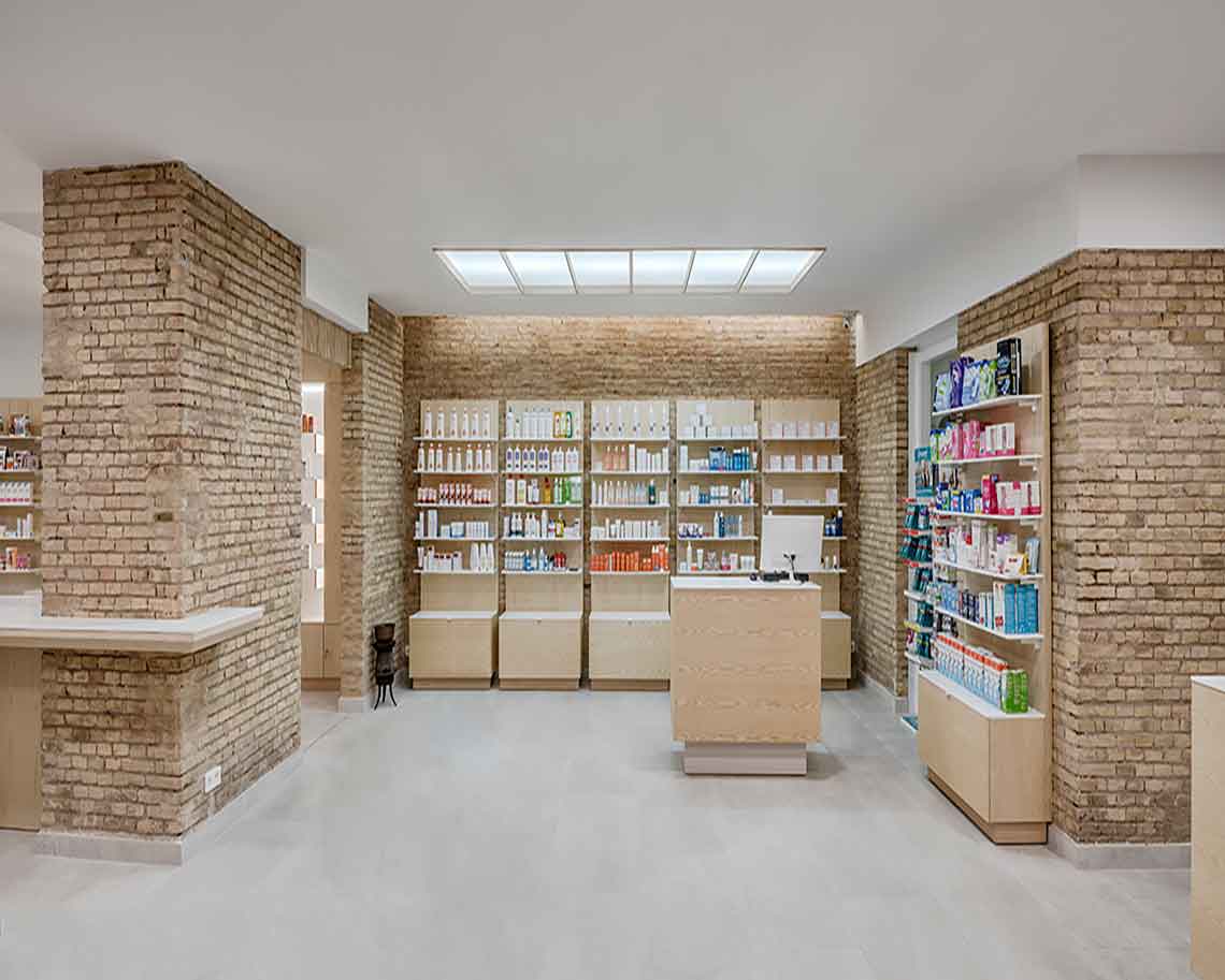 Farmacia moderna con estanterías de productos y paredes de ladrillo visto iluminadas por lucernario