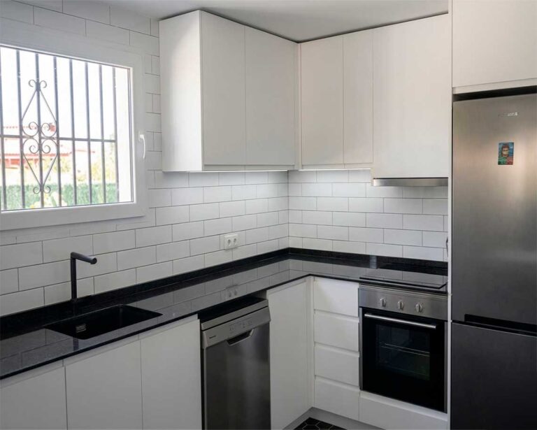 Una cocina que vuelve a cobrar vida 1 cocina moderna blanca en forma de L con encimera negra muebles minimalistas y electrodomésticos integrados