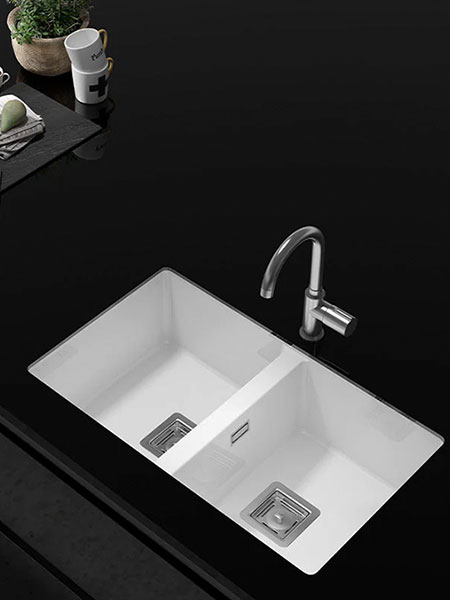 Fregadero blanco de resina Roc Stone de doble cubeta instalado sobre encimera negra de cocina moderna