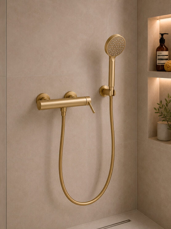 Conjunto de ducha monomando de pared en acabado dorado cepillado con ducha de mano, flexo metálico y soporte mural en baño moderno.