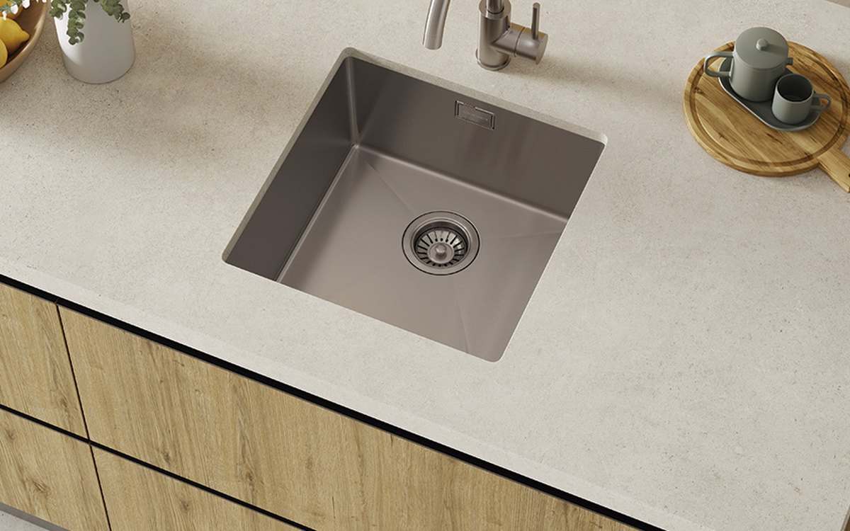 Fregadero de acero inoxidable de una cubeta bajo encimera clara en una cocina de madera